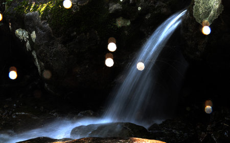 Waterfall in a dark cave with light from a lanterns.の写真素材