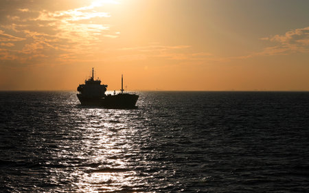 Silhouette of a cargo ship in the sea at sunset.の写真素材
