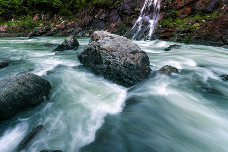 Long exposure of a waterfall flowing over rocks and boulders in the forestの写真素材