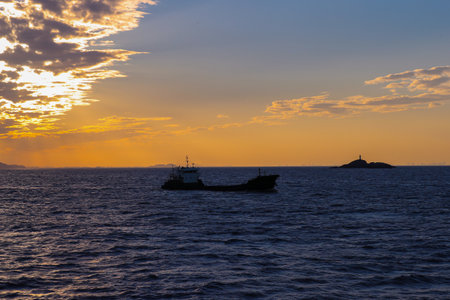 Silhouette of a fishing boat in the sea at sunset.の写真素材