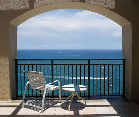 An inviting view of the ocean and a boat through an arch of a balcony.の写真素材