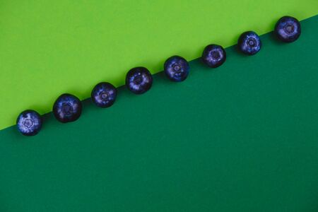 Blueberries on a green background close-up, top view. There is a place for inscription.