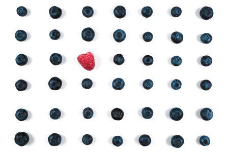 Blueberry pattern on a white background in the middle with raspberries. View from above.