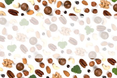 A pattern of nuts on a white background, decorated with green leaves. View to the top, there is a place for inscription.の写真素材