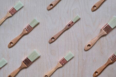 New paint brushes located diagonally against a plywood background. View from above. There is a place...