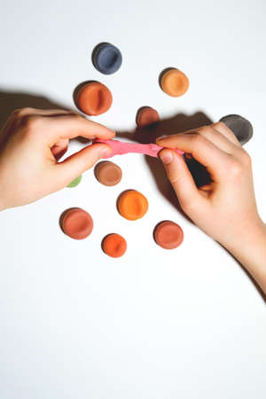 Childs hands close-up with plasticine. On a white isolated background. Svehu view. There is a place for an inscription.の写真素材