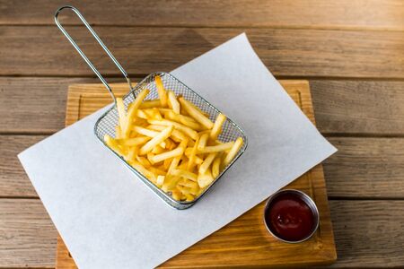 french fries in iron grid and sauce on a wooden table gray backgroundの写真素材