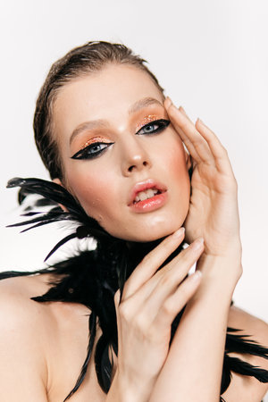 Beautiful girl with smoky eyes make-up, plume of black feathers