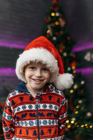 smiling cute and handsome boy in christmas pajamas, christmas background with christmas treeの写真素材