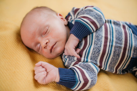 two week old very cute baby in overalls on an orange plaidの写真素材