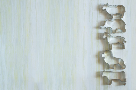Border of molds for biscuits in the shape of animals on a light wooden surfaceの写真素材