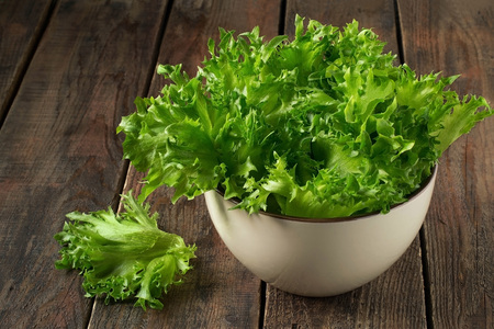 Fresh green salad in a bowl on a wooden background
