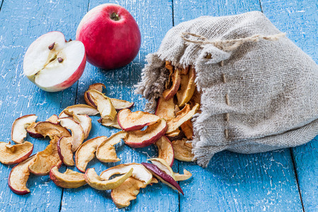Dried apples in a linen bag and fresh ripe apples on a blue painted table. Selective focusの写真素材