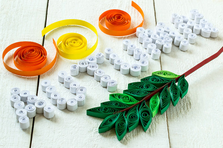 Word Autumn and leaf of a mountain ash in the technique quilling, paper strips in spirals on a white wooden background. Selective focusの写真素材
