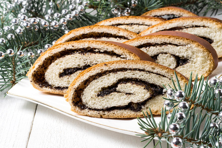 Roll with poppy seeds on a white plate and Christmas decorations on the table. Selective focusの写真素材