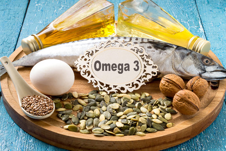 Products - source fatty acids Omega 3 (mackerel, camelina oil, rapeseed oil, organic egg, pumpkin and flax seeds, walnuts) on a round wooden boardの写真素材