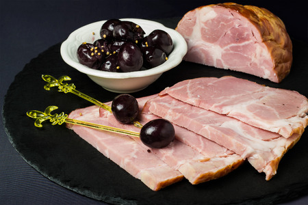 Baked ham with pickled grapes on a slate round blackboardの写真素材