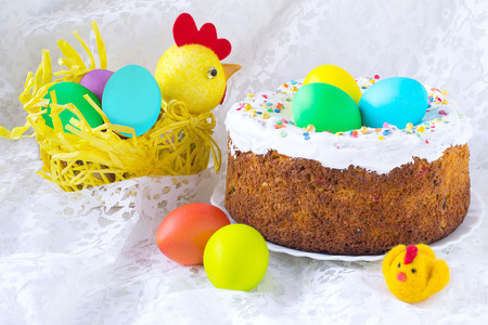 Traditional Easter treats: cakes and colorful easter eggs on a white lace tablecloth