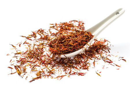 Dried safflower petals (false saffron, saffron thistle, carthamus tinctorius) in the spoon on a white backgroundの写真素材