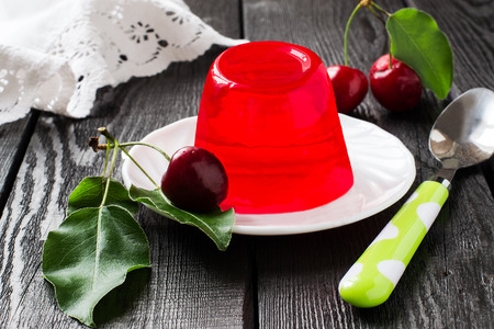 Delicious cherry jelly and ripe cherries with leaves on a dark wooden table. Selective focusの写真素材