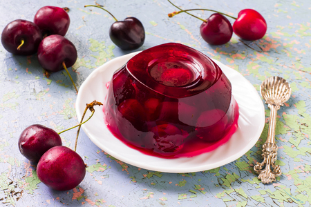 Delicious cherry jelly and ripe cherries with leaves on old blue table. Selective focusの写真素材
