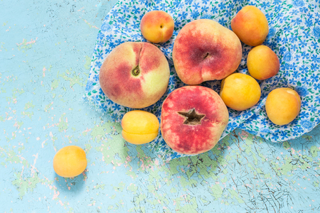 Fresh organic flat peaches and apricots on old blue table. Top viewの写真素材