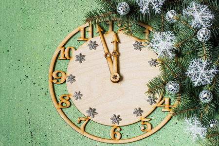 Decorative clock showing midnight and the arrival of the New Year, decorated Christmas tree branch...
