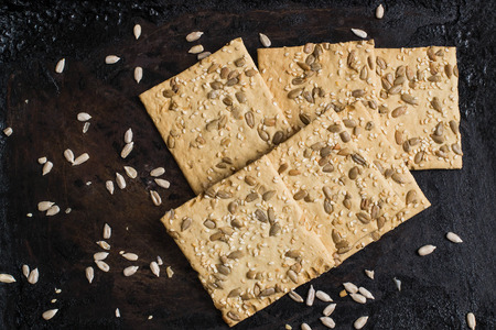 Homemade wholegrain crackers with sunflower seeds and sesame on an old iron pan. The concept of diet...