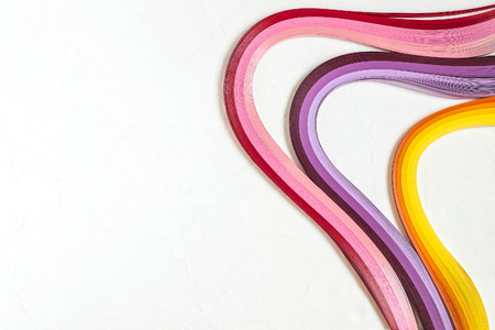 Bright multi-colored strips for quilling on a white background