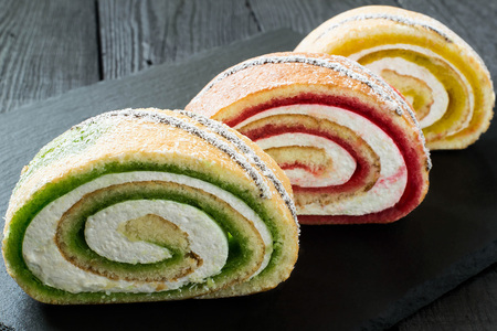 Delicious cake roll with fruit marmalade (kiwi, strawberry, lemon) and marshmallow. Sliced rolls on...