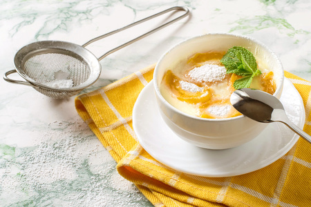 Delicious creamy apricot dessert in white cup on yellow napkin. Sieve with powdered sugar. Summer desserts with fruits. Dietary and healthy foodの写真素材