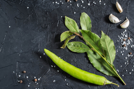 Bay leaf, chili pepper, garlic, sea salt and allspices on black textured background. Seasoning, spices, hot and spicy vegetablesの写真素材