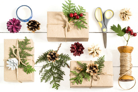 Homemade gift box decoration for Christmas. DIY hobby. Boxes are wrapped in kraft paper, tied with...