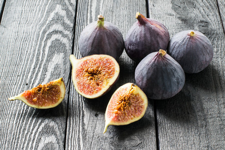 Ripe fresh figs on dark wooden background. Whole fruits, half and slices. Source of potassium, calcium, phosphorus, vitamins B, PP, A, C. Contains substances for prevention of cardiovascular diseasesの写真素材