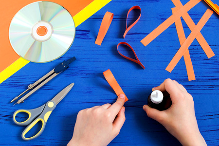 Child makes smiling sun from CD. Children's art project. DIY concept. Step-by-step photo...