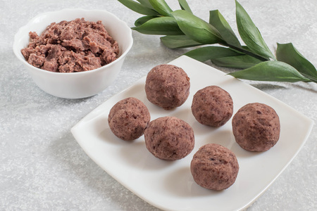 Sweet bean paste in bowl and balls of bean paste on light gray background. Widely used in Asian...