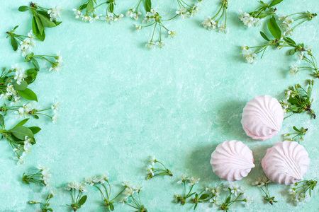 Delicate frame of marshmallows and cherry blossoms. Delicious airy dessert. Concept of light air desserts as gentle spring flowersの写真素材