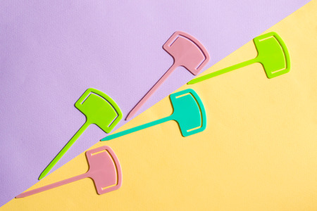 Multicolored small plastic pointers without inscriptions on two-color paper background. Trendy flat...