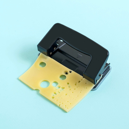 Punching holes in cheese using punch. Minimal style. Creative, imagination and fantasy. Funny idea...