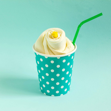 Socks paper cup with peas with straws on blue pastel background. Imitation of festive cocktail. Minimal style. Creative idea, imagination and fantasy. Holiday conceptの写真素材
