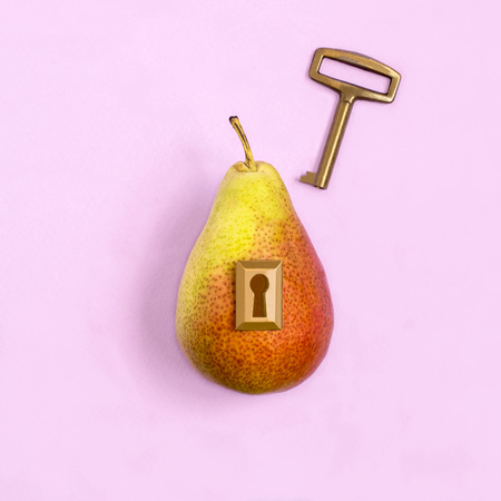 Ripe pear with lock and key on pastel lilac background. Minimal style. Creative idea, imagination and fantasy. Original food concept: key to diet and healthy eatingの写真素材