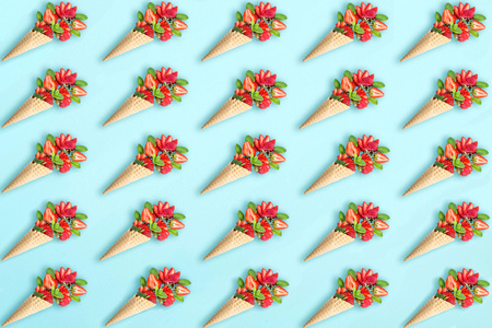 Blue background with strawberry and mint in waffle cone. Minimal style. Concept of delicious summer desserts. Flat lay, top viewの写真素材