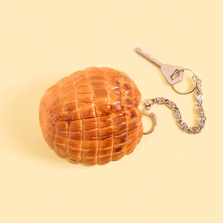 Meatloaf as keychain with key on pastel yellow background. Minimum style. Creative idea, imagination and fantasy. Original food concept: good recipe is key to delicious foodの写真素材