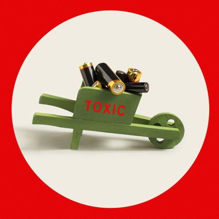 Many used alkaline batteries in wooden cart with word toxic. Attention to problem of environmental...