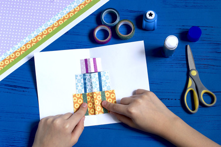 Child makes card with 3D gifts for Christmas. DIY concept