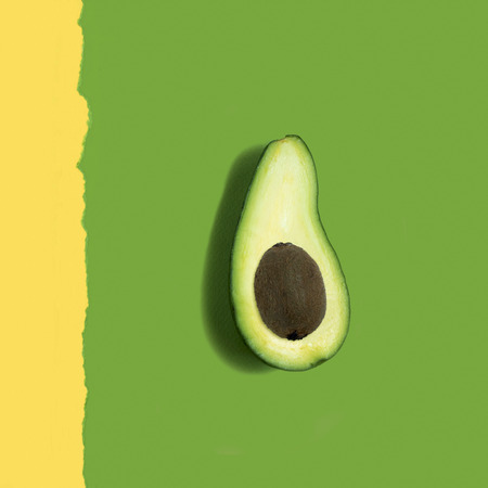 Avocado with kiwi instead of seed on a two-color paper background