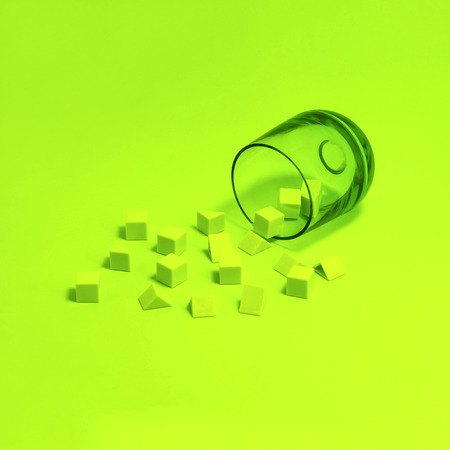 Small green cubes and pyramids scattered out of green glass on green background. Minimal monochrome image. Color gameの写真素材