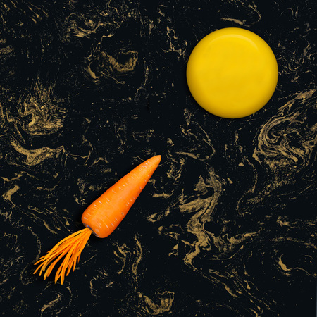 Carrot rocket flies to plate in form of moon. Black with gold background. Concept of healthy food, energy and vitamin products. Creative idea, imagination and fantasy. Minimal styleの写真素材