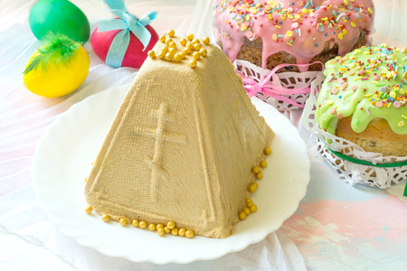 Caramel cottage cheese dessert (Paskha), Easter cakes with icing sugar and colorful painted eggs on...