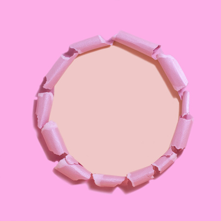 Pink torn paper with hole against peach-colored background. Minimal abstract colorful backgroundの写真素材